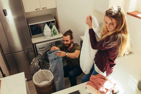 A couple folding clothes in a laundry room